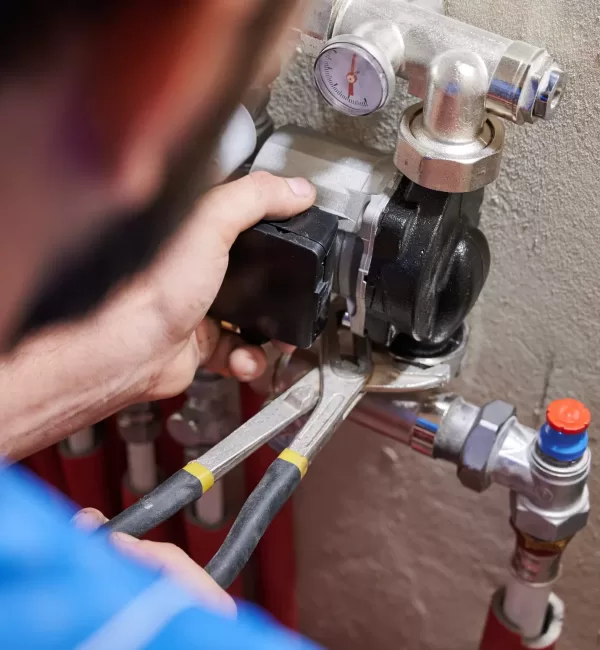 Close up of worker hands using wrenches, installing water pump in apartment. Man plumber working on heating system installation. Concept of radiator installation, plumbing works and home renovation.